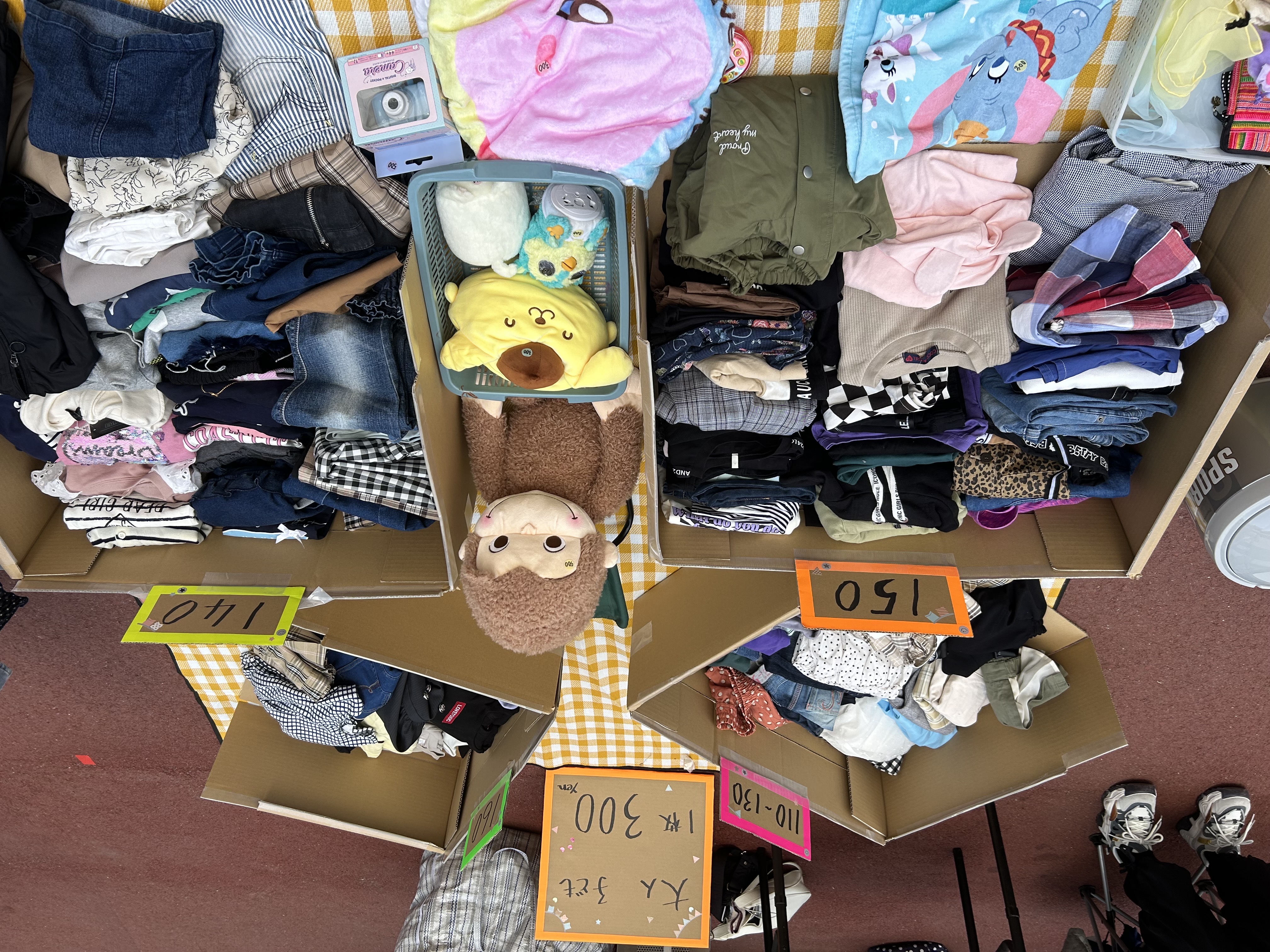 ブースの展示例 - 整理された子ども服とおもちゃの販売ブース